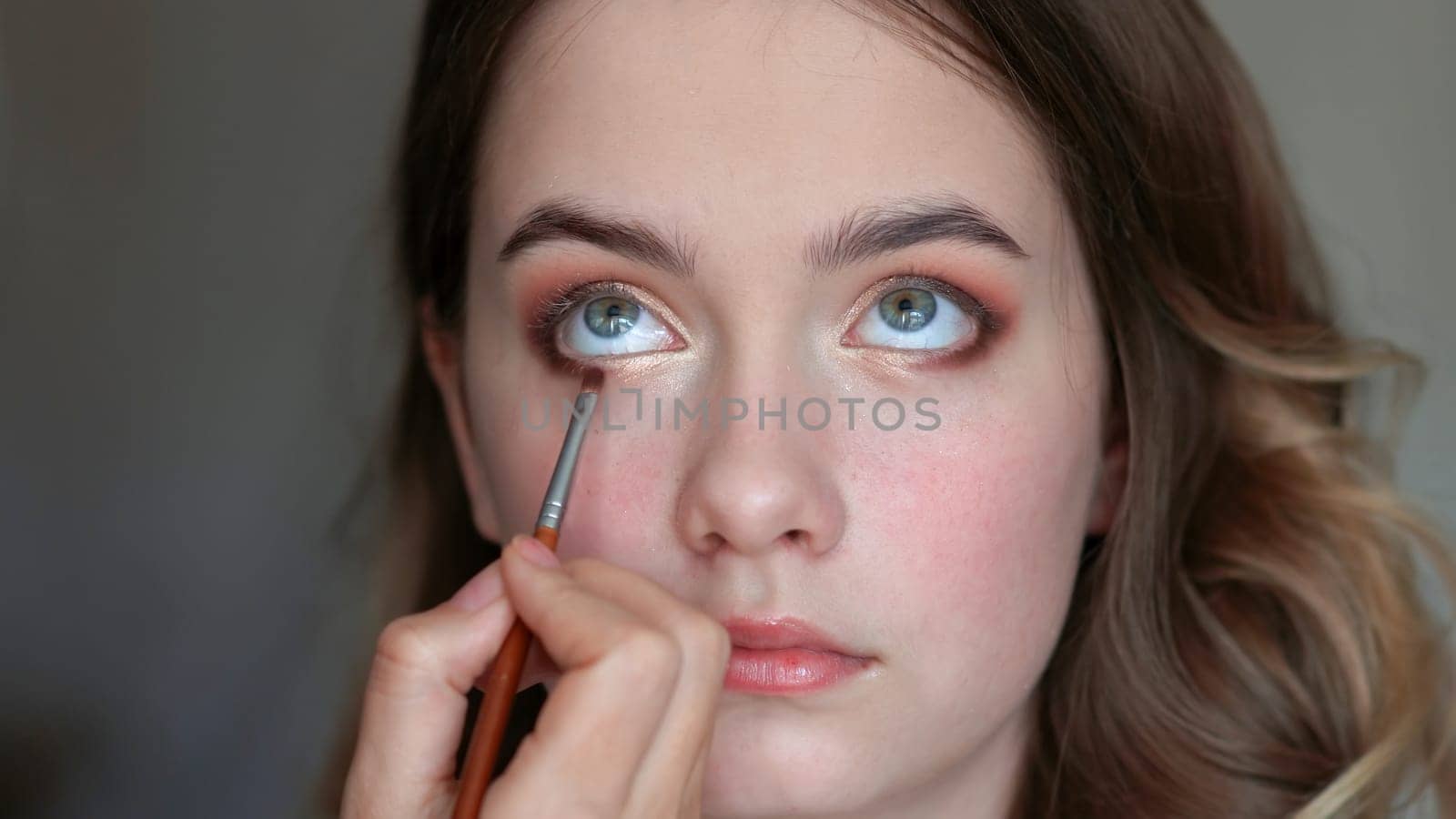 Girl makeup artist paints the eyes of a young girl.