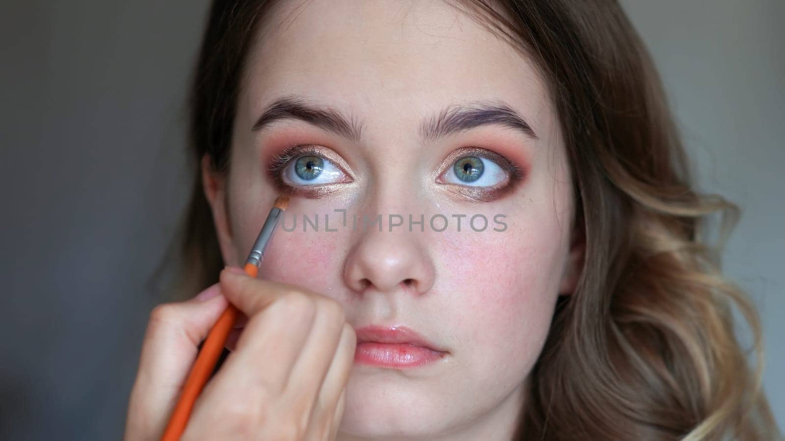 Girl makeup artist paints the eyes of a young girl by DovidPro
