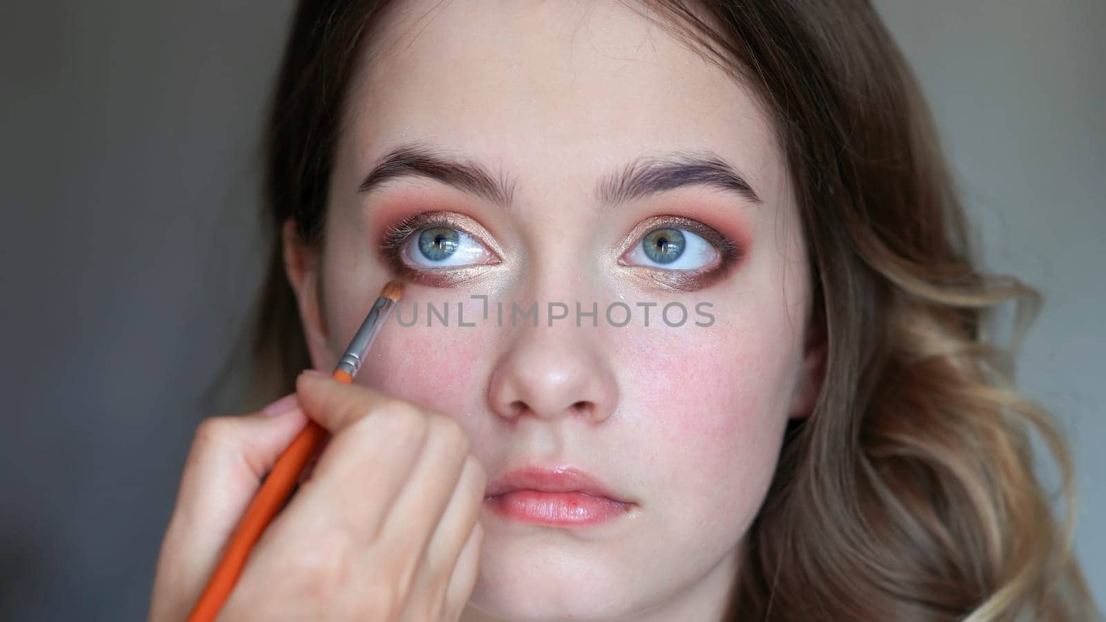 Girl makeup artist paints the eyes of a young girl.