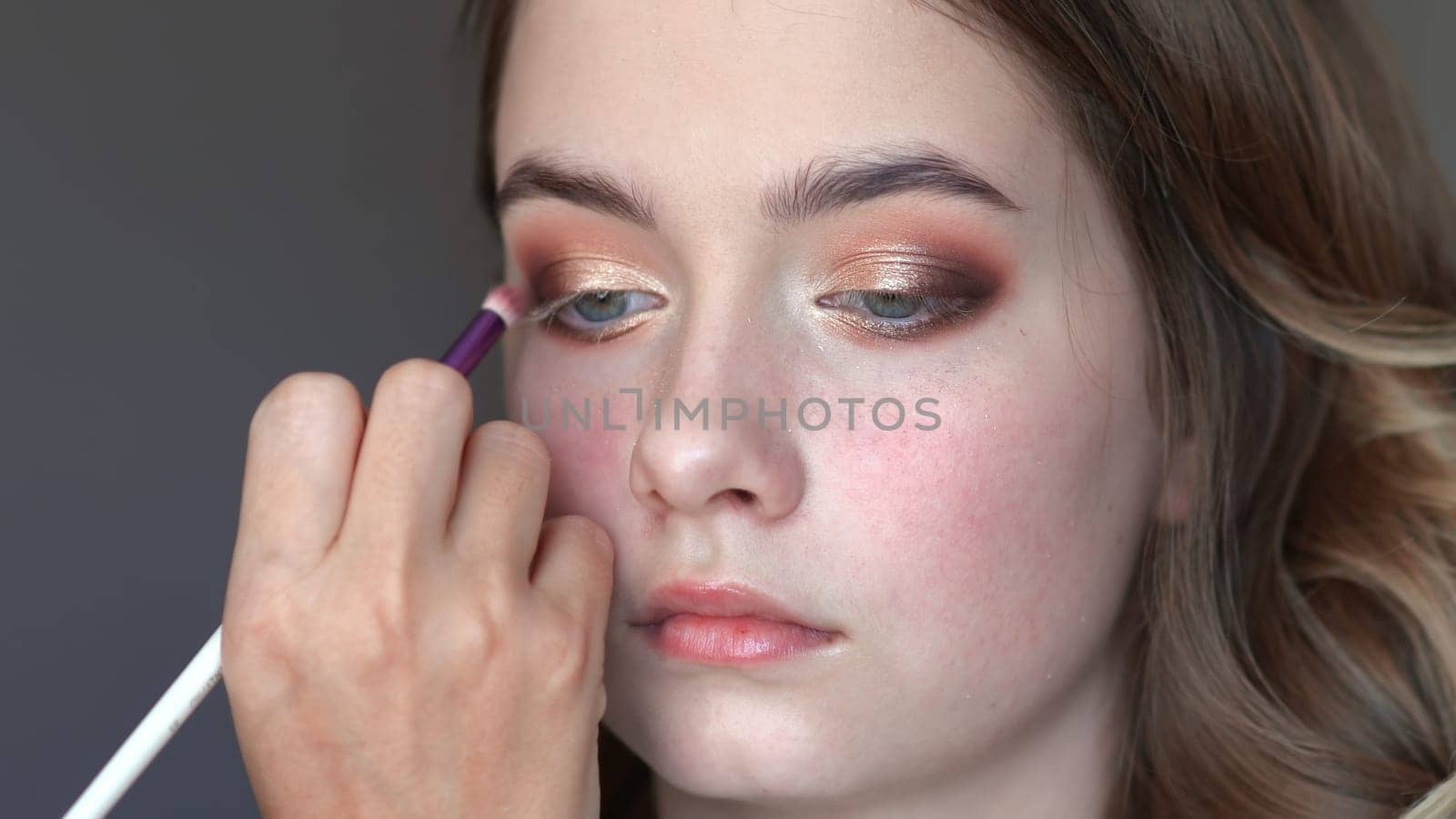 Girl makeup artist paints the eyes of a young girl.