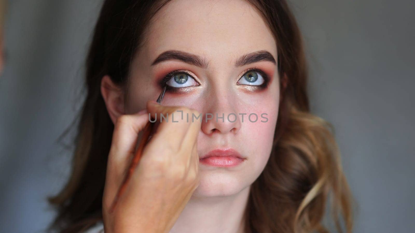 Girl makeup artist paints the eyes of a young girl by DovidPro
