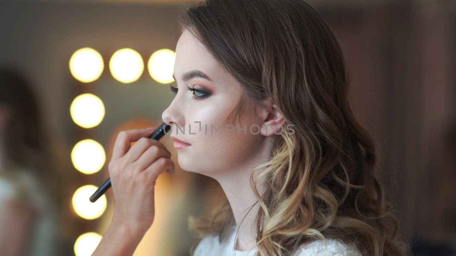 Makeup artist applies powder on the face of a 16 year old girl