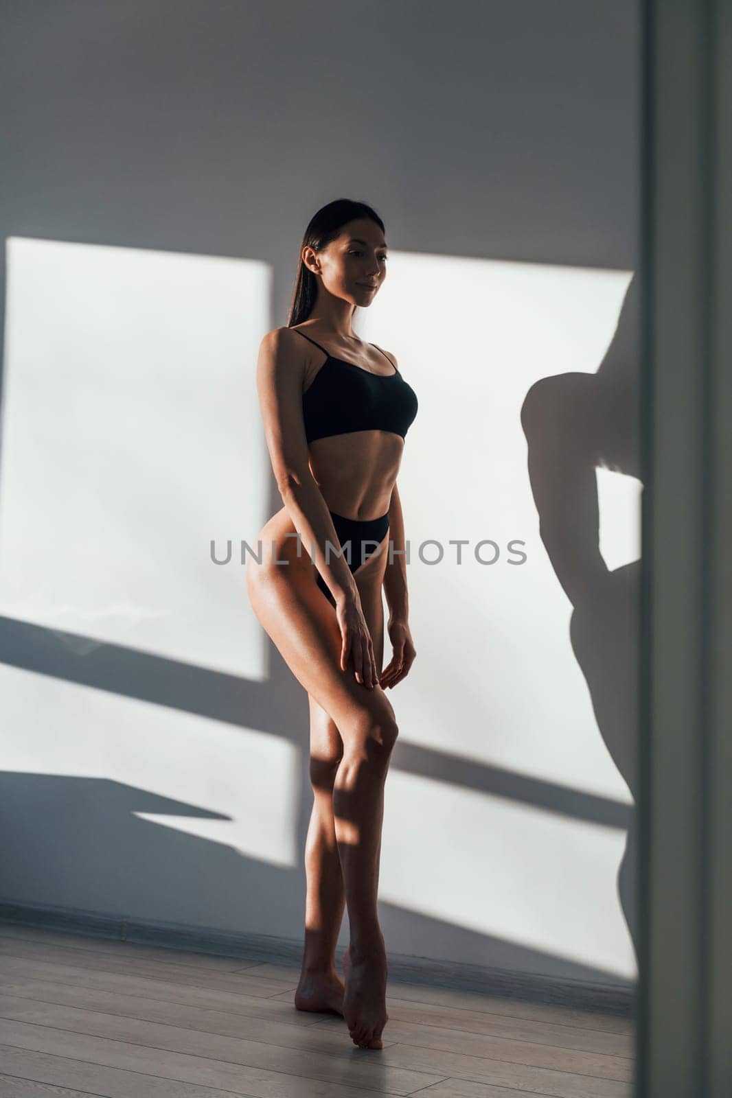 In black underwear. Young caucasian woman with slim body shape is indoors at daytime.