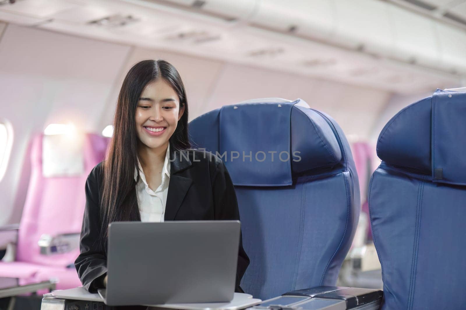Female passenger sitting on plane while working on laptop computer with simulated space using on board wireless connection..