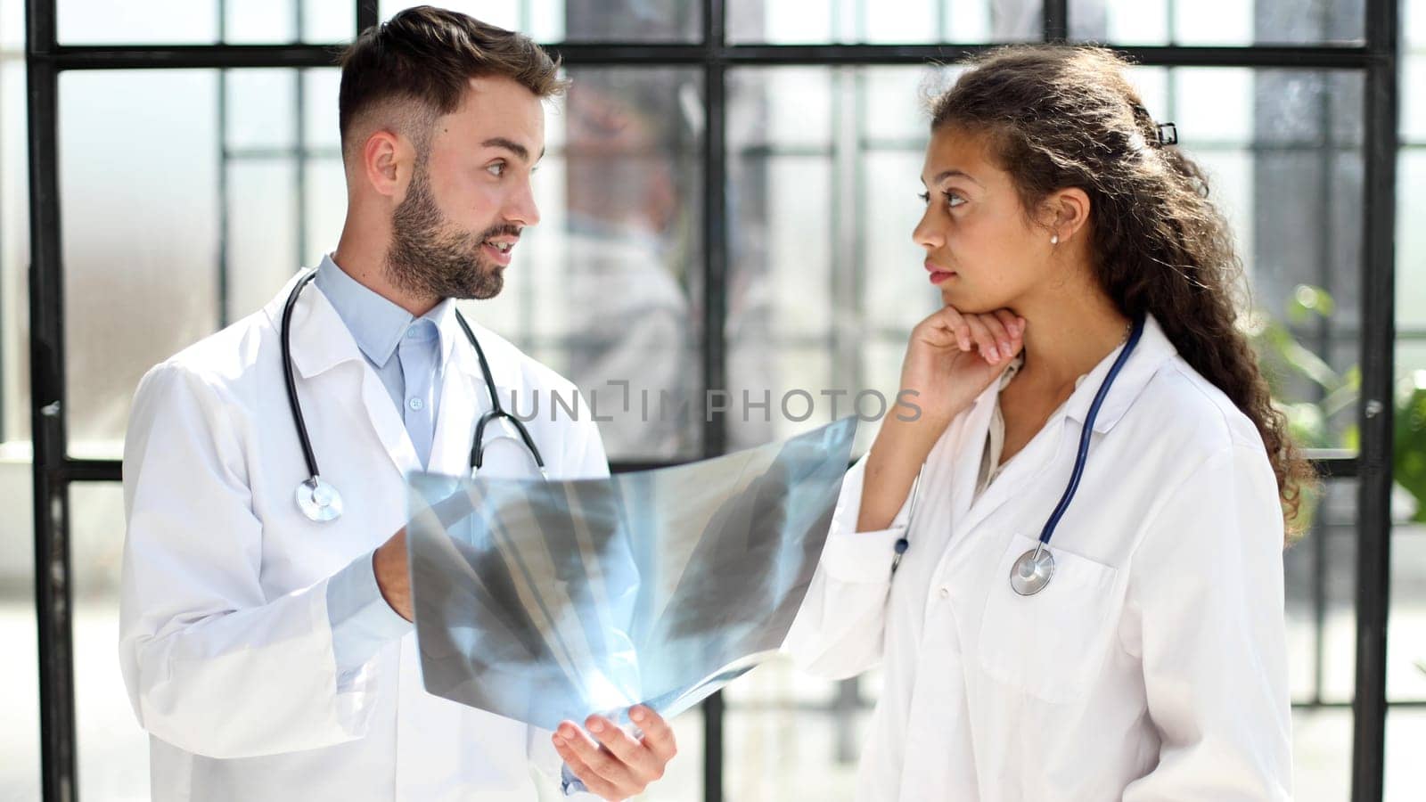 Two busy doctors working with papers and x-rays in hospital lobby