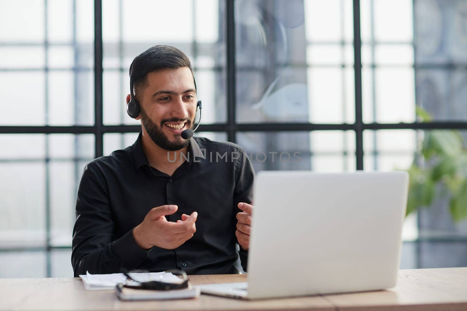Positive businessman talking on headset at a computer