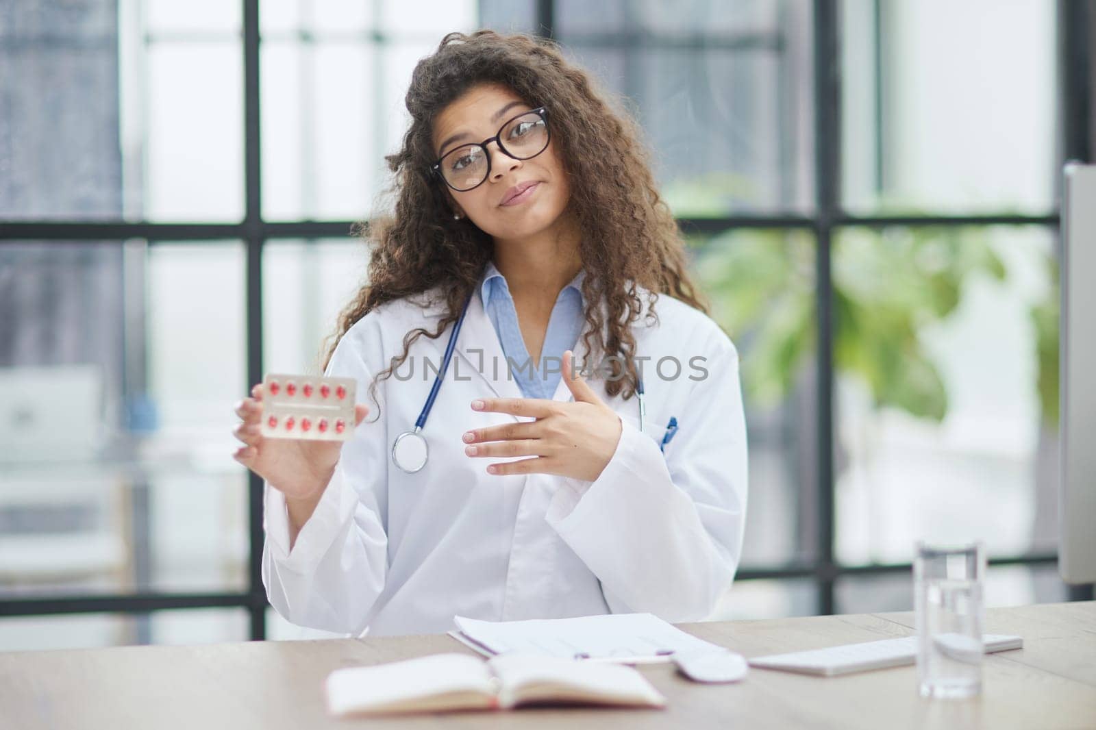 Portrait of young female doctor in white coat at workplace