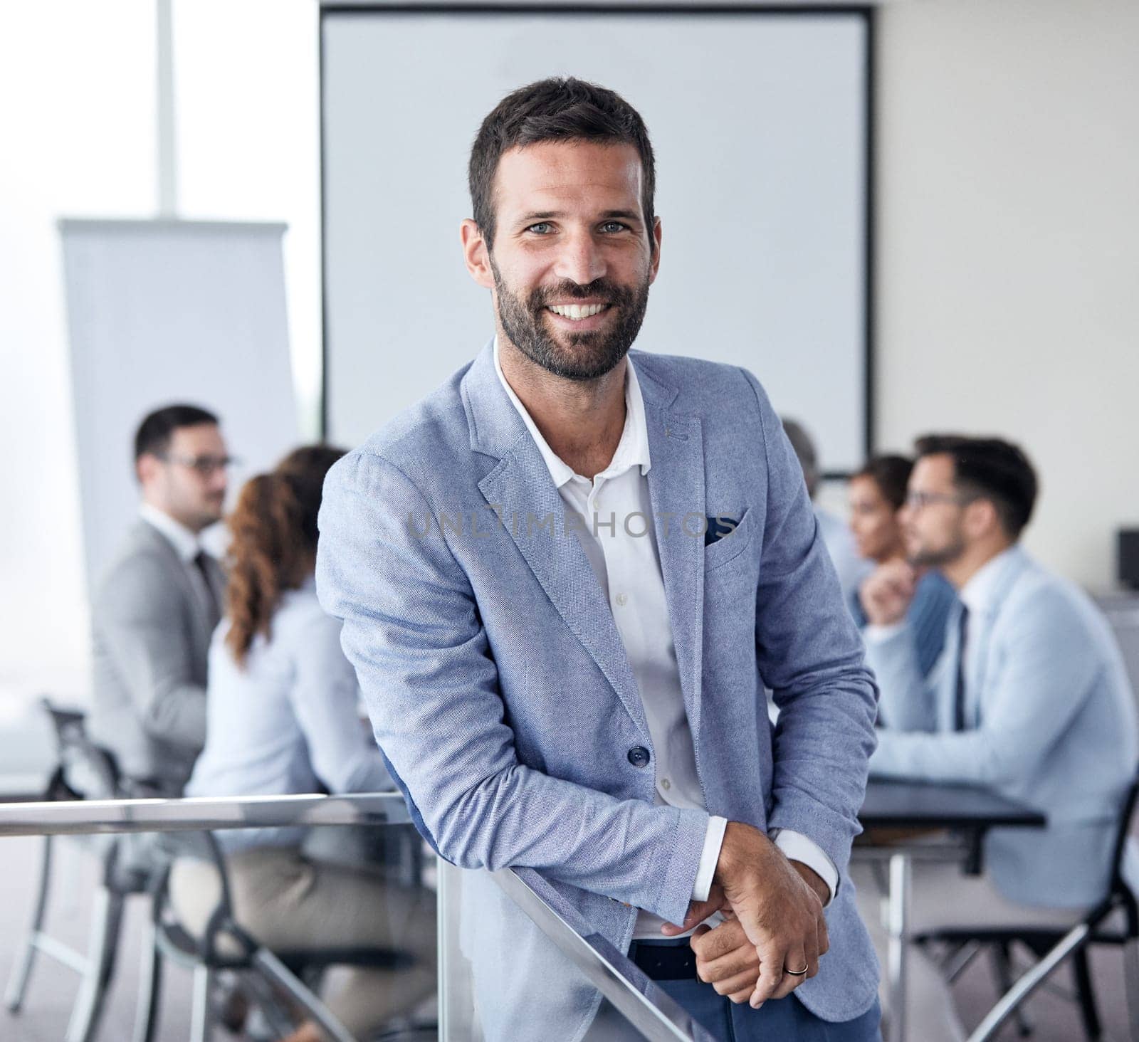 A portrait of a young smiling businessman during a meeting and presentation in the office. Business concept