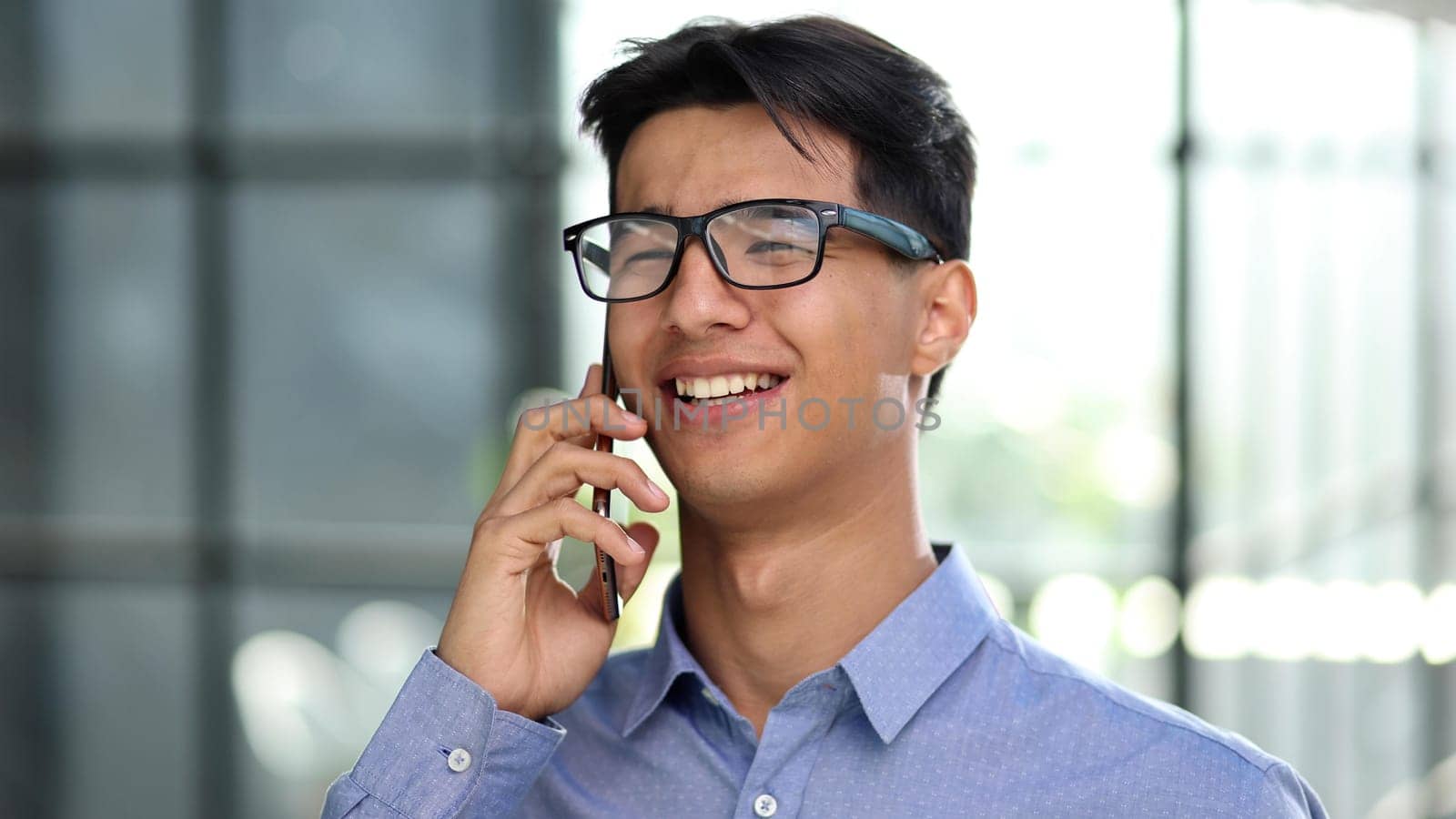 A businessman makes a phone call while standing in the lobby of a modern office. close-up