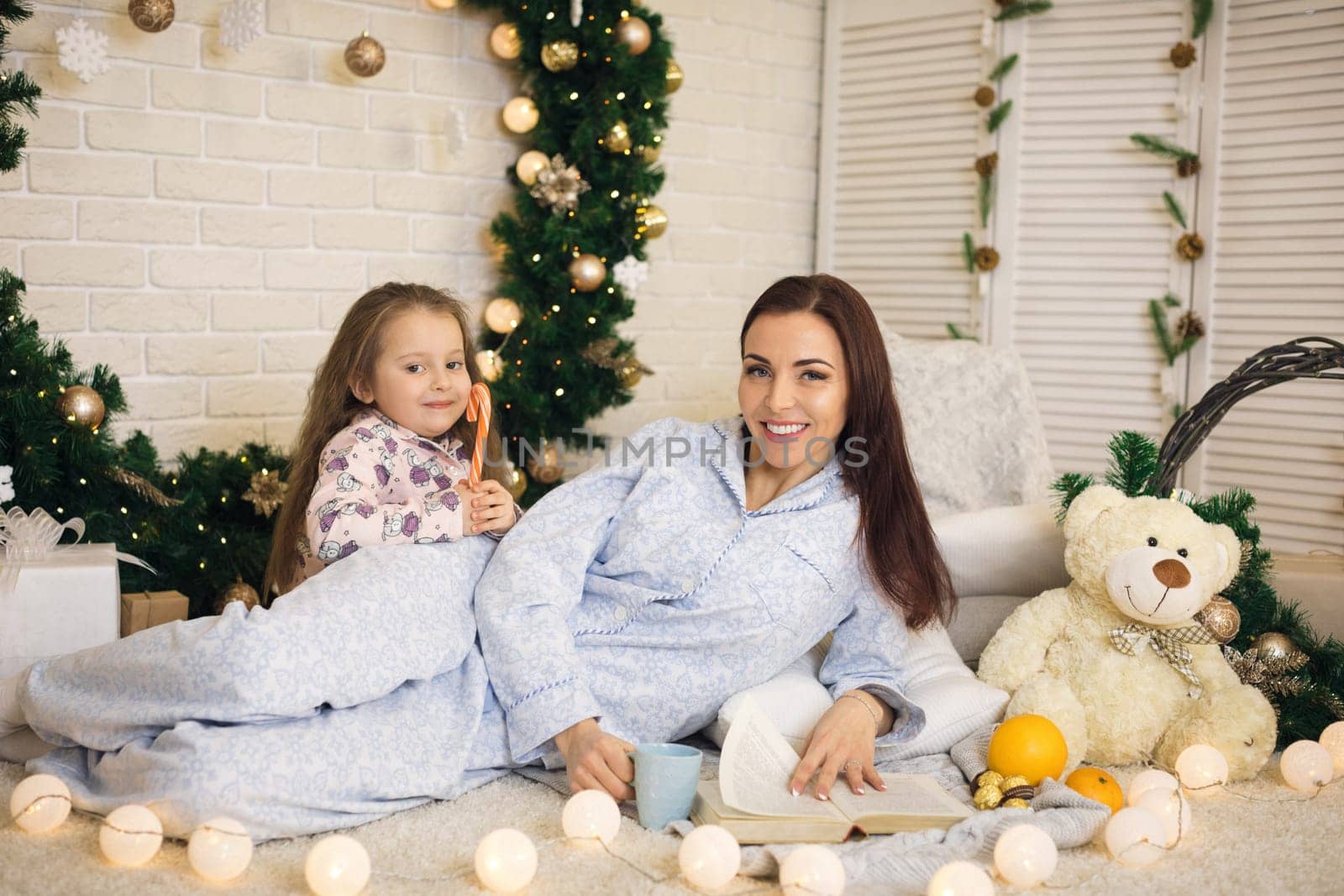 happy mother with her little child daughter playing near the Christmas tree