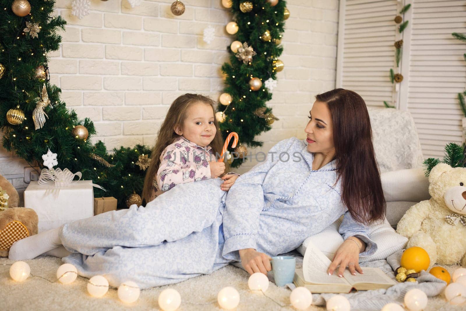 happy mother with her little child daughter playing near the Christmas tree