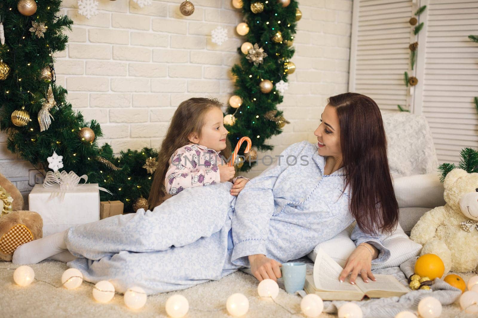 happy mother with her little child daughter playing near the Christmas tree