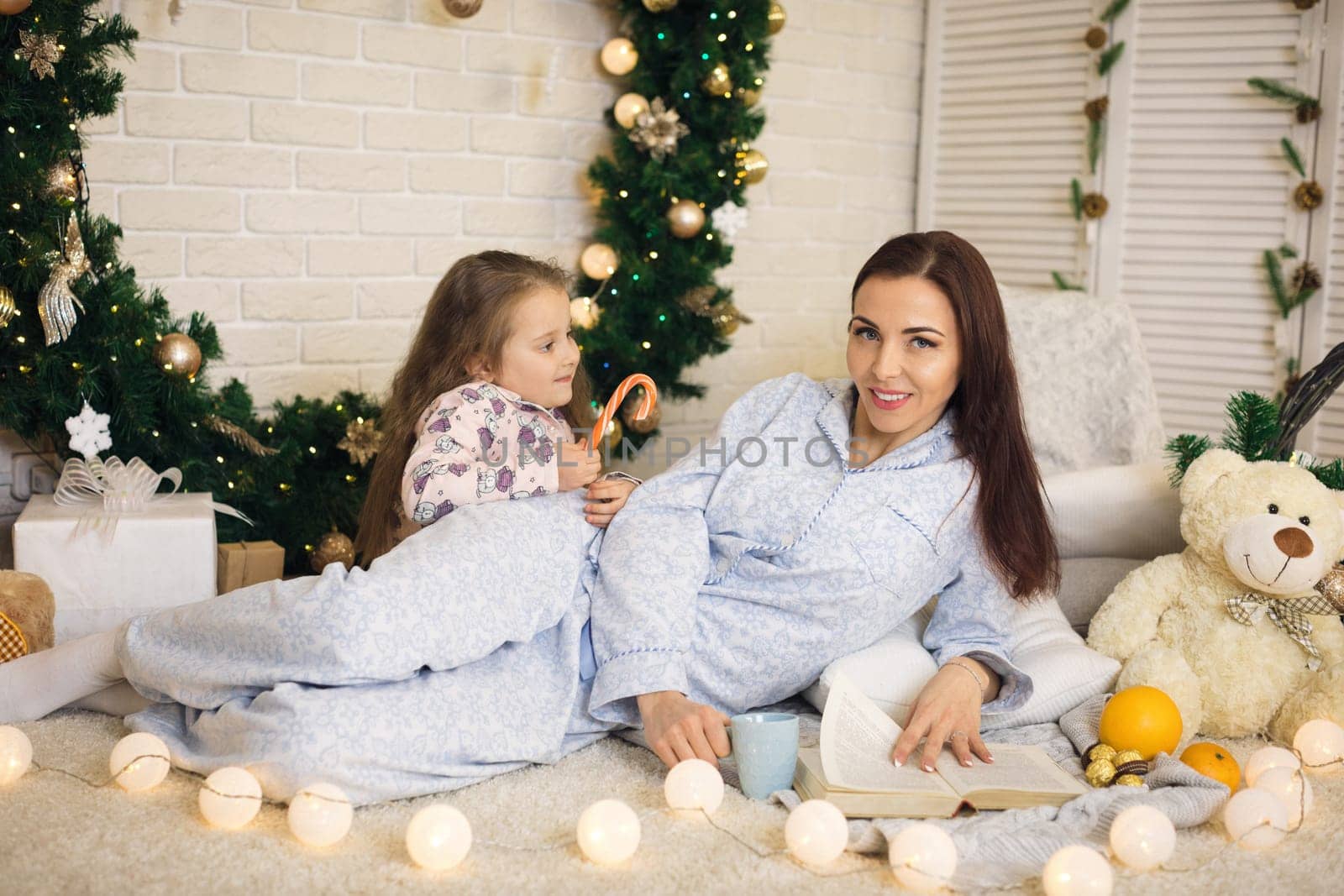 happy mother with her little child daughter playing near the Christmas tree