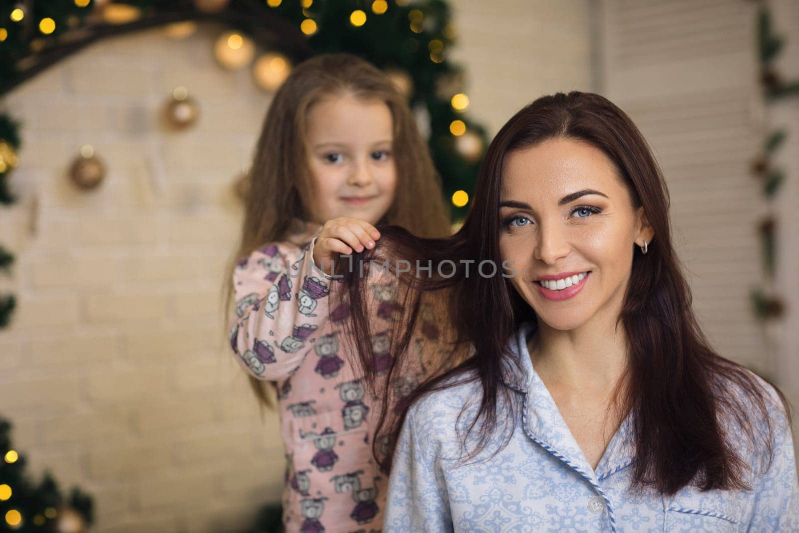 happy mother with her little child daughter playing near the Christmas tree