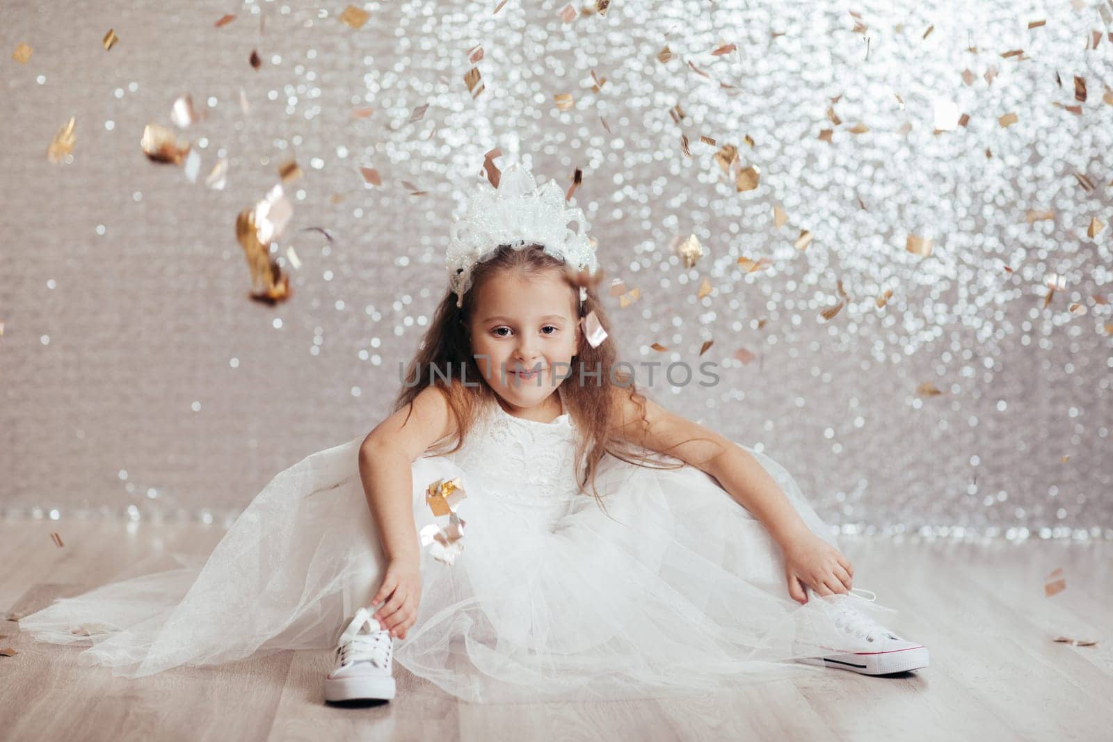 cute little child girl in princess dress on confetti background with silver bokeh. birtday party