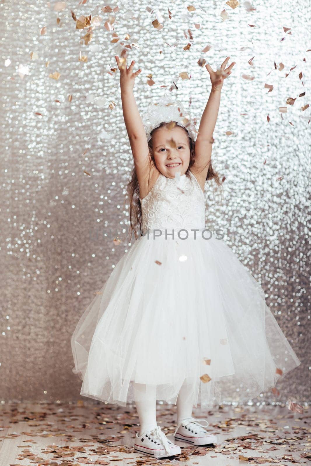 cute little child girl in princess dress on confetti background with silver bokeh. birtday party