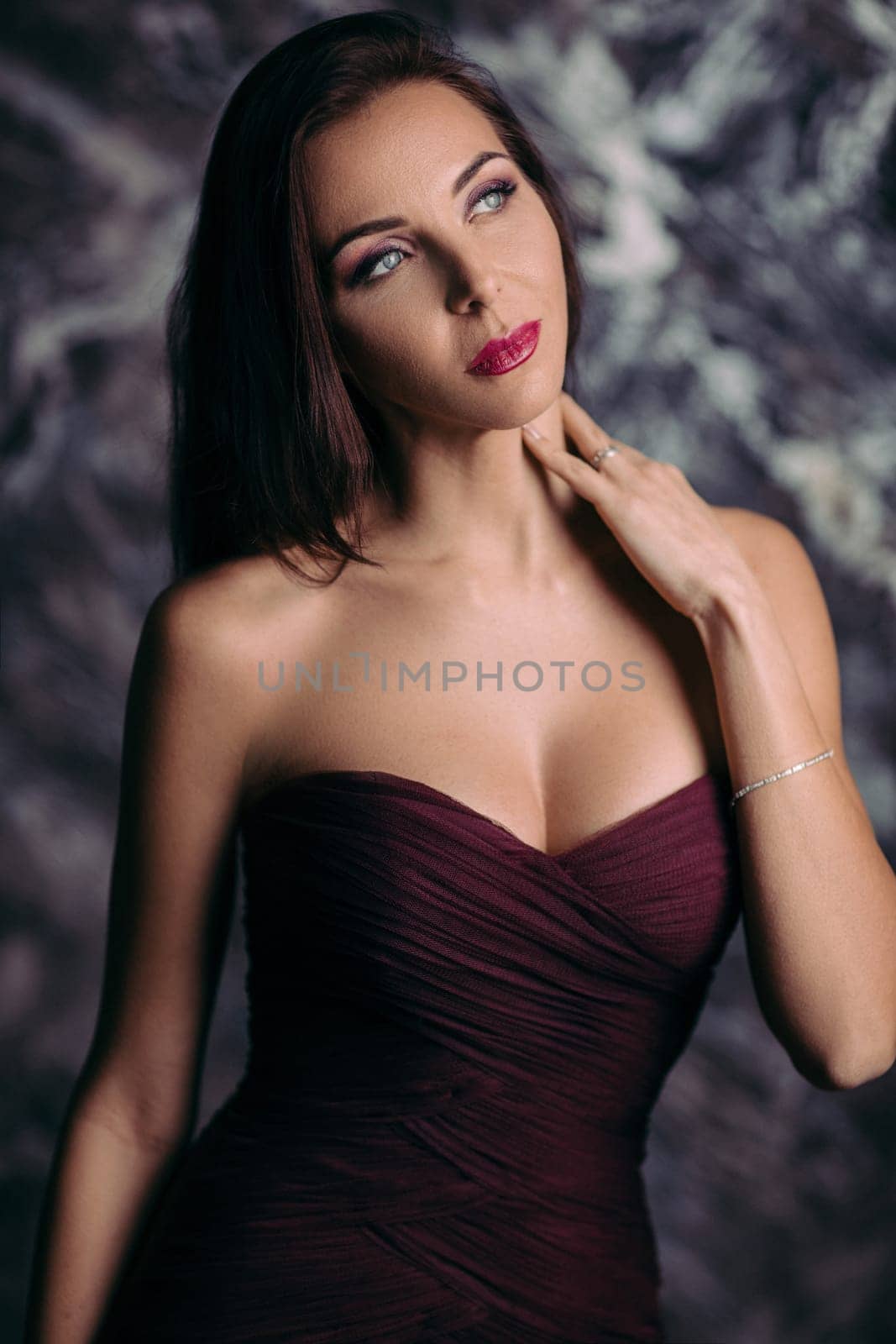 Portrait of magnificent sexy woman in evening dress posing over dark background
