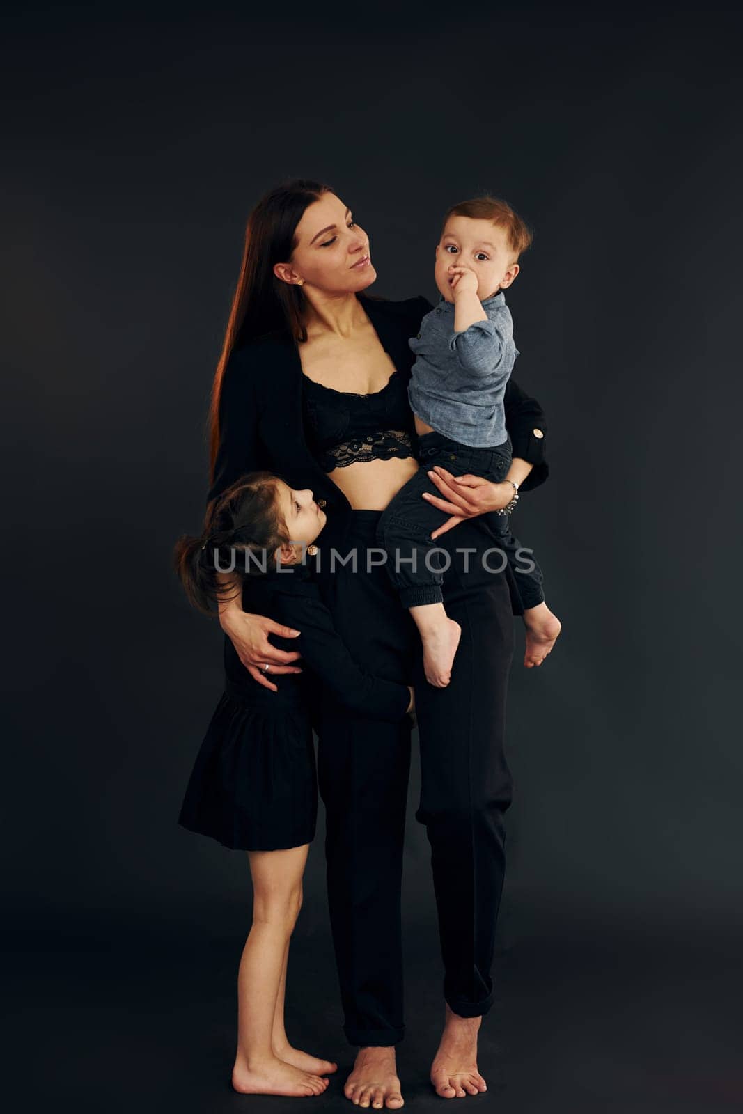 Woman in black stylish clothes is with her little son and daughter in the studio by Standret
