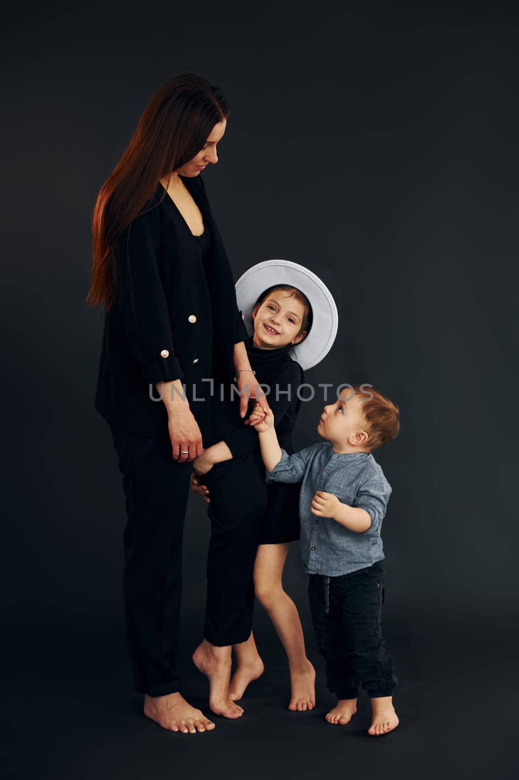 Woman in black stylish clothes is with her little son and daughter in the studio by Standret