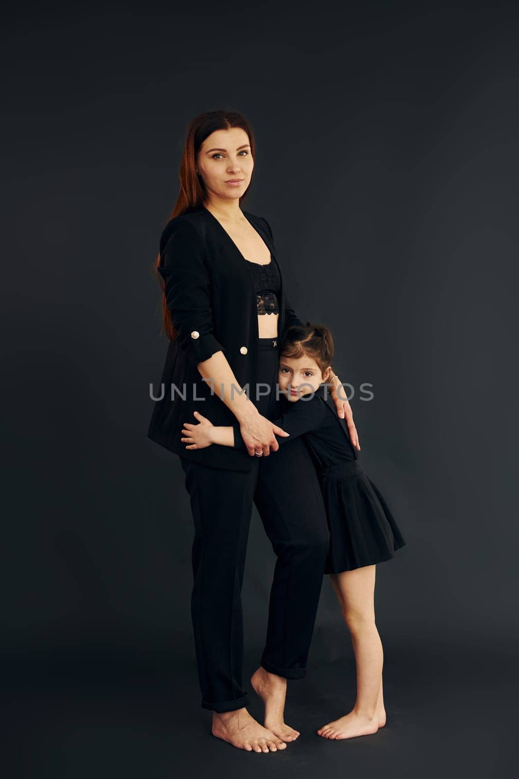 Mother and daughter is together in the studio against black background.