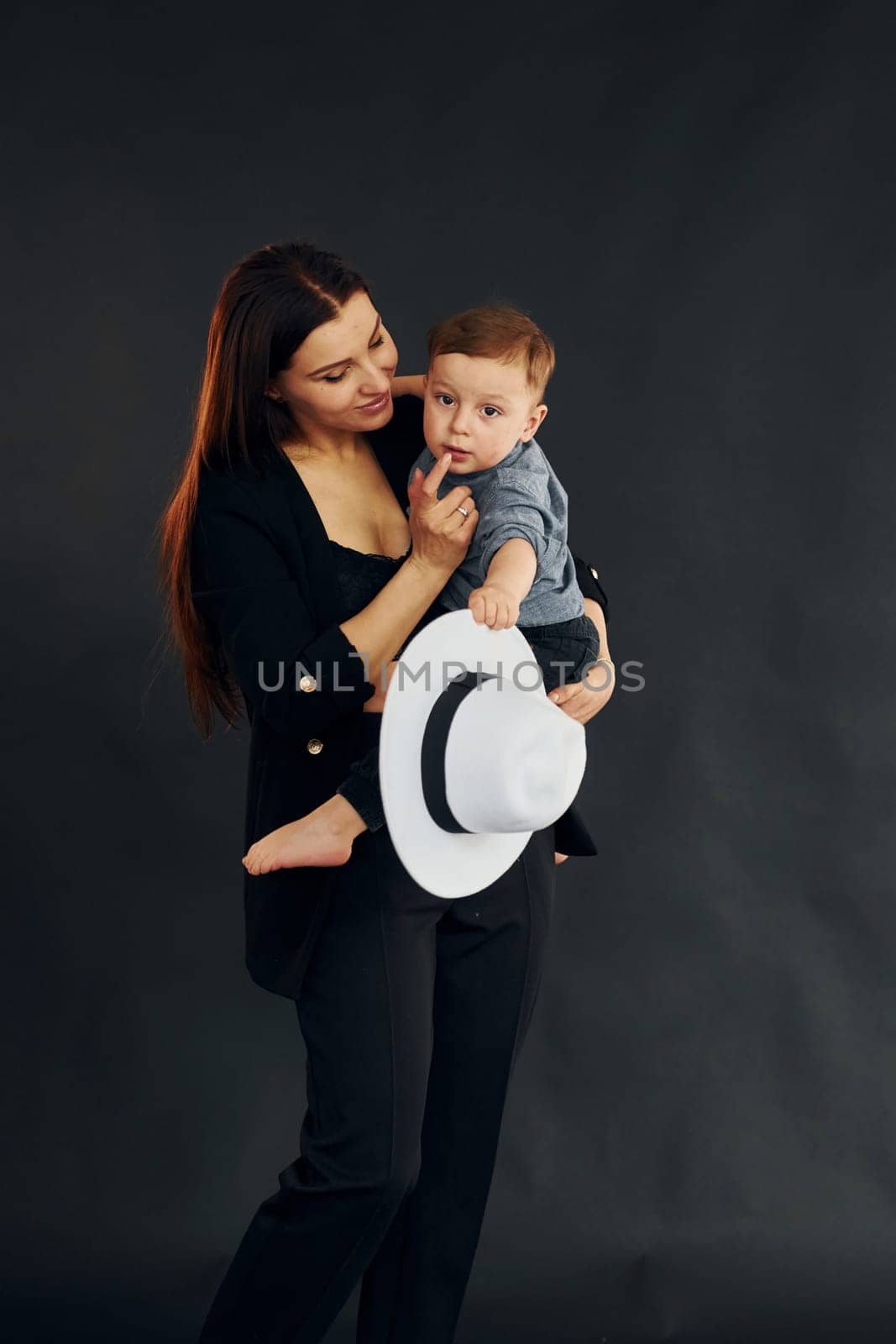 Mother in stylish black clothes is with her little son in the studio by Standret