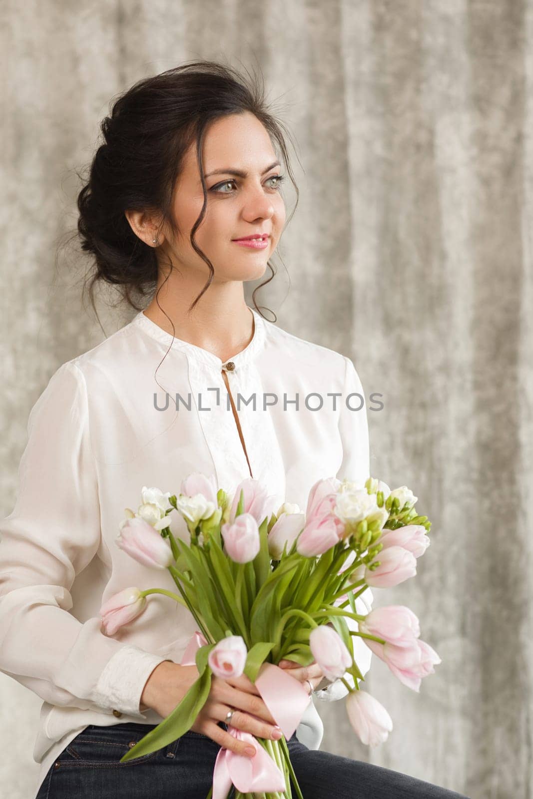 portrait of a beautiful brunette woman with a bouquet of tulips flowers