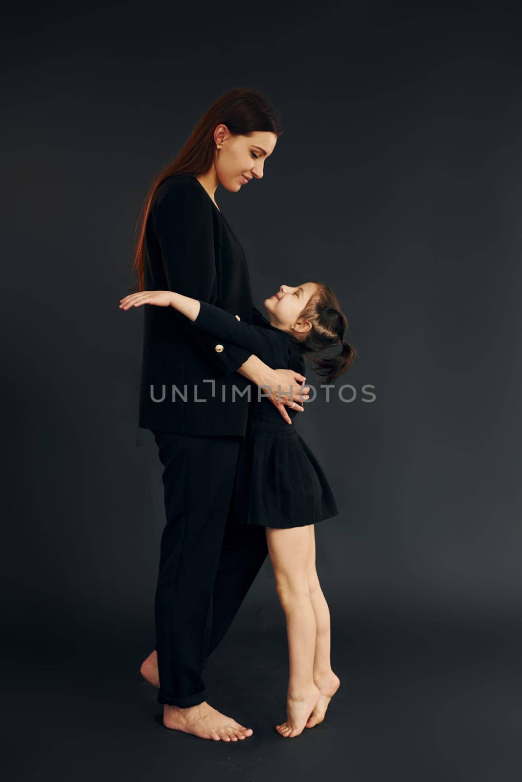 Mother and daughter is together in the studio against black background.