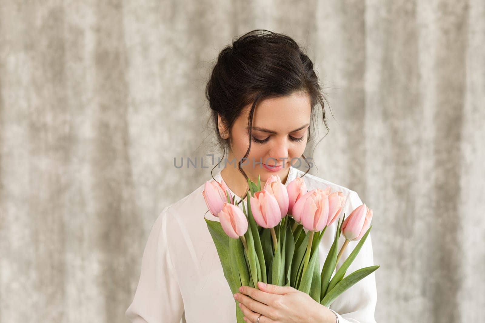 portrait of a beautiful brunette woman with a bouquet of tulips flowers