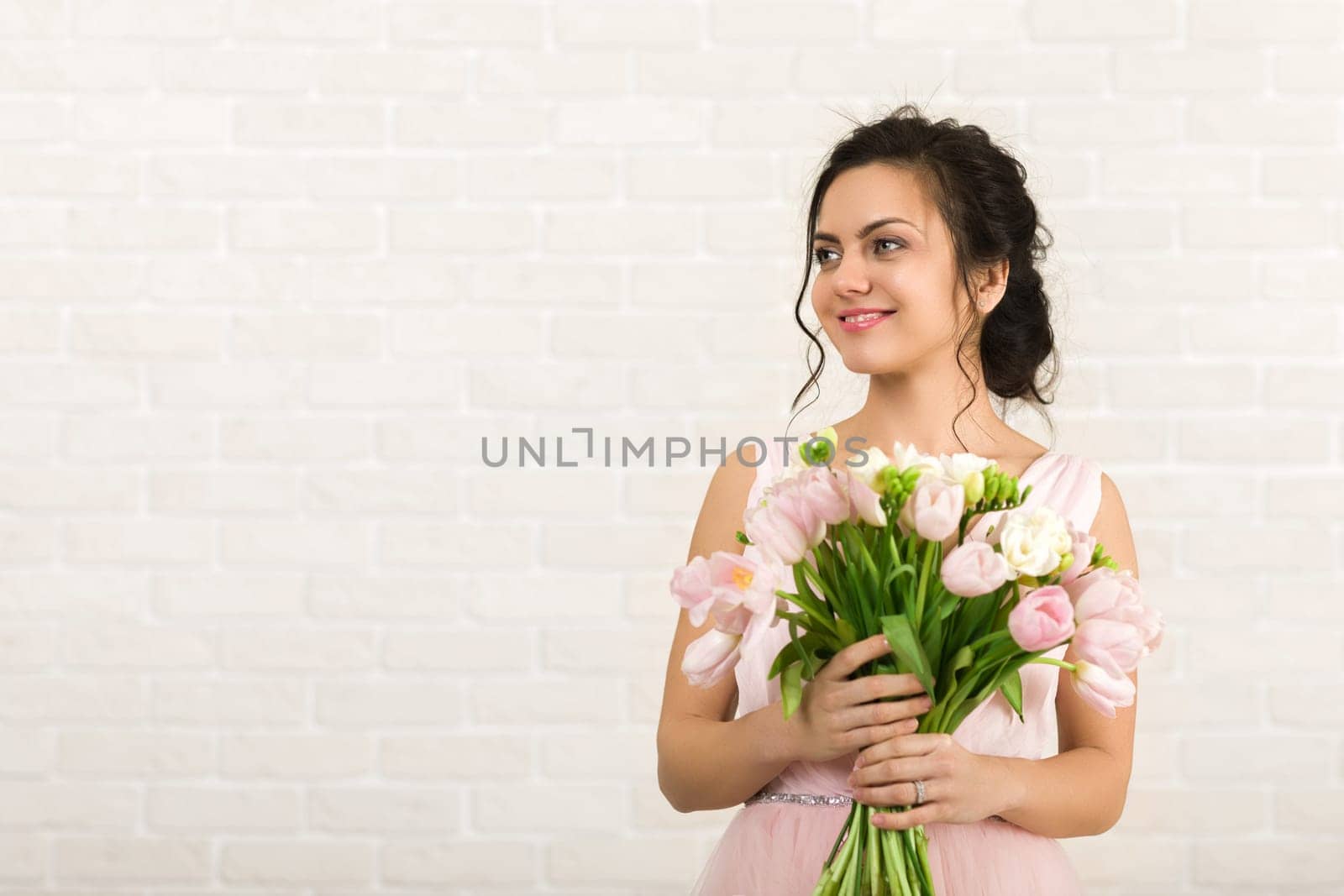Portrait of beautiful bride with wedding bouquet of pink tulips