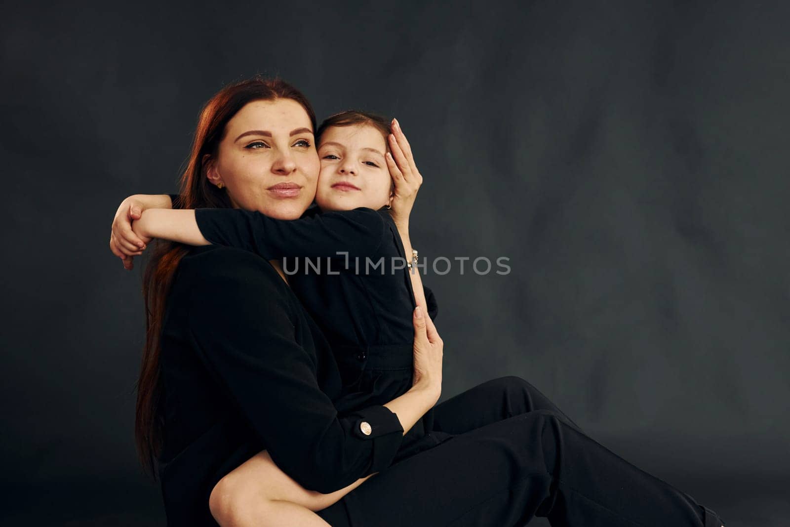 Mother and daughter is together in the studio against black background.