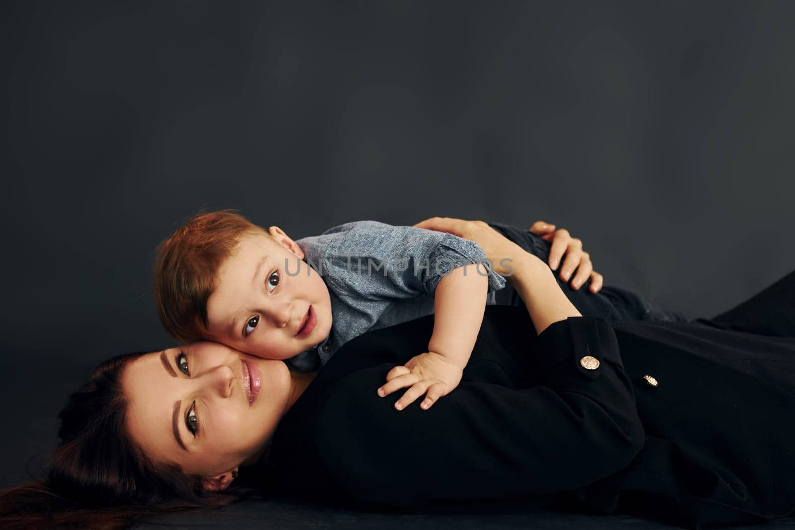 Mother in stylish black clothes is with her little son in the studio by Standret