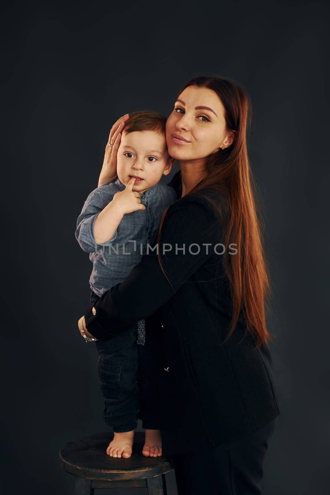 Mother in stylish black clothes is with her little son in the studio by Standret