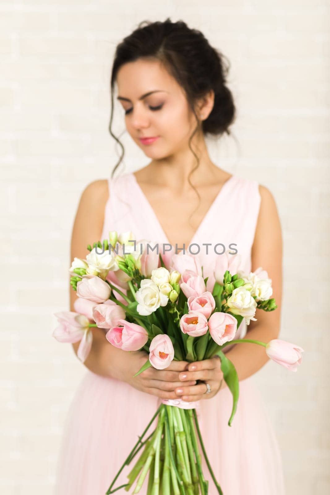 Portrait of beautiful bride with wedding bouquet of pink tulips