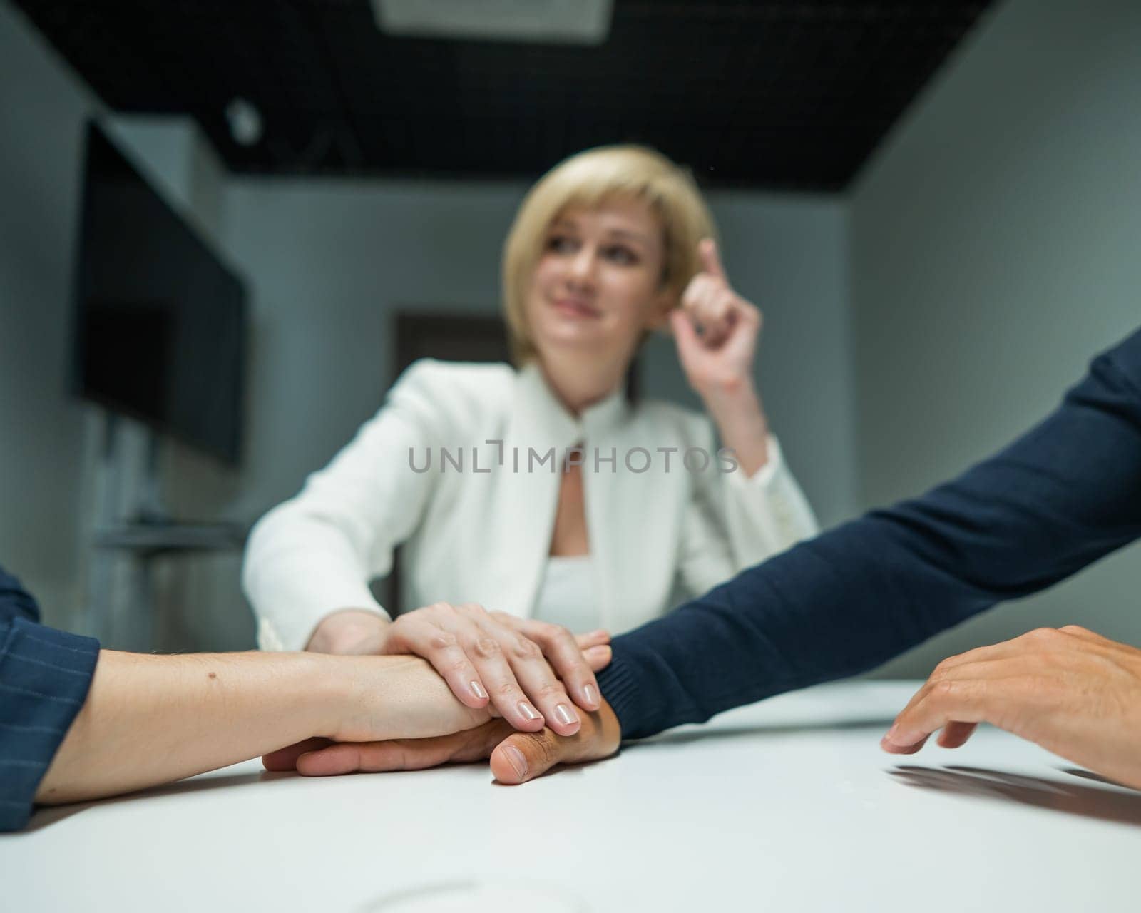 Blond, red-haired woman and bearded man dressed in suits in the office. Business people shake hands making a deal in a conference room. by mrwed54