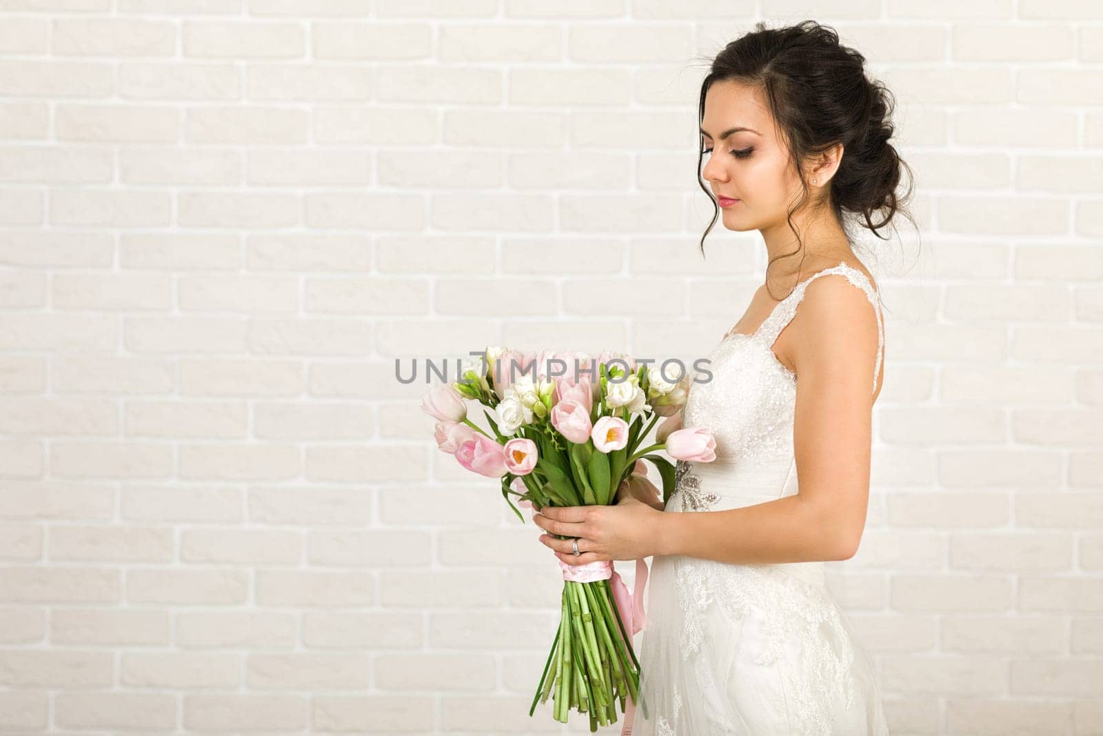 Portrait of beautiful bride with wedding bouquet of pink tulips
