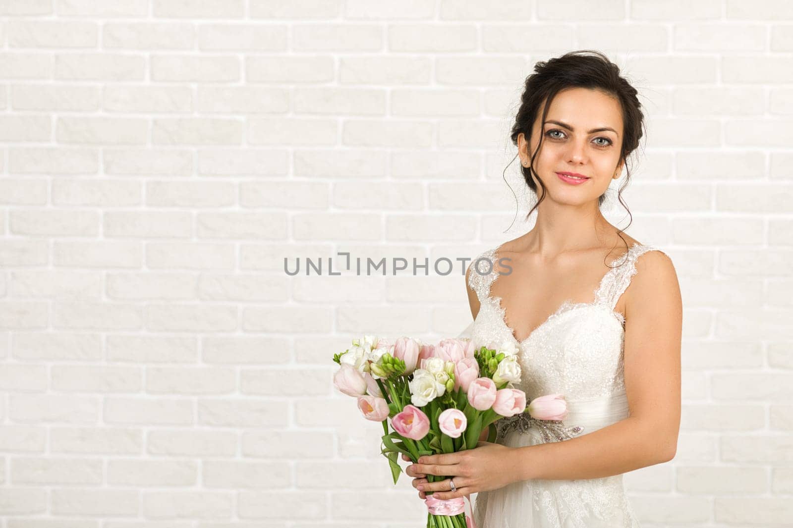 Portrait of beautiful bride with wedding bouquet of pink tulips