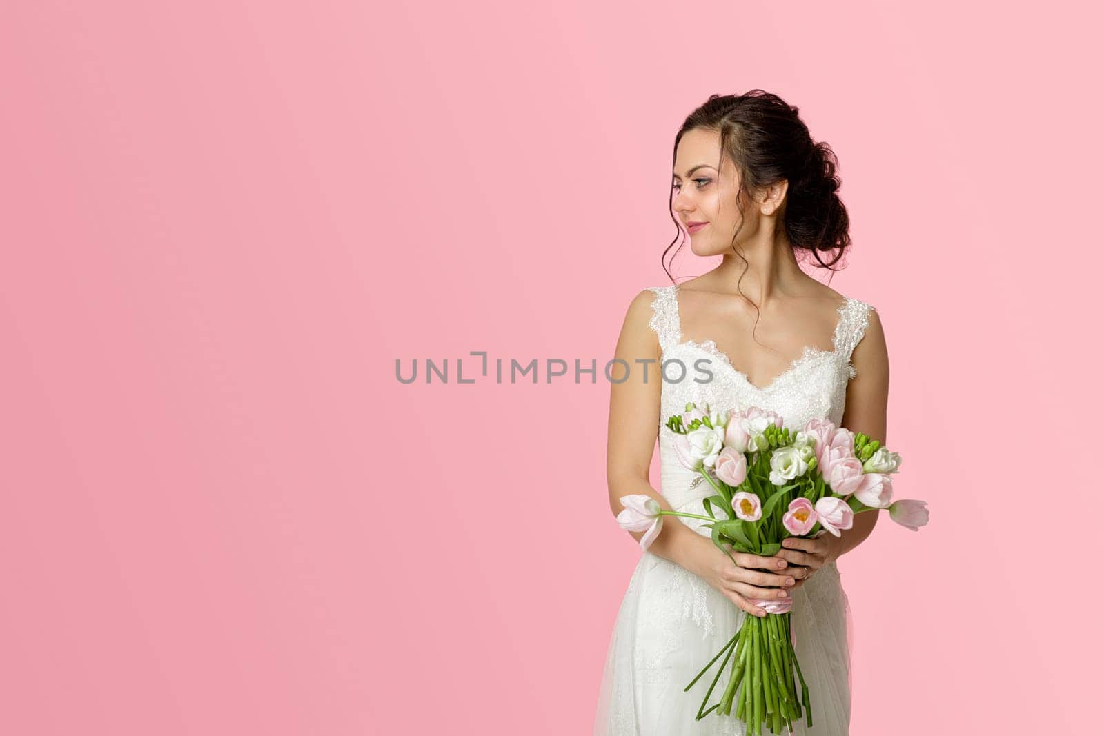 beautiful bride with wedding bouquet of pink tulips on pink background