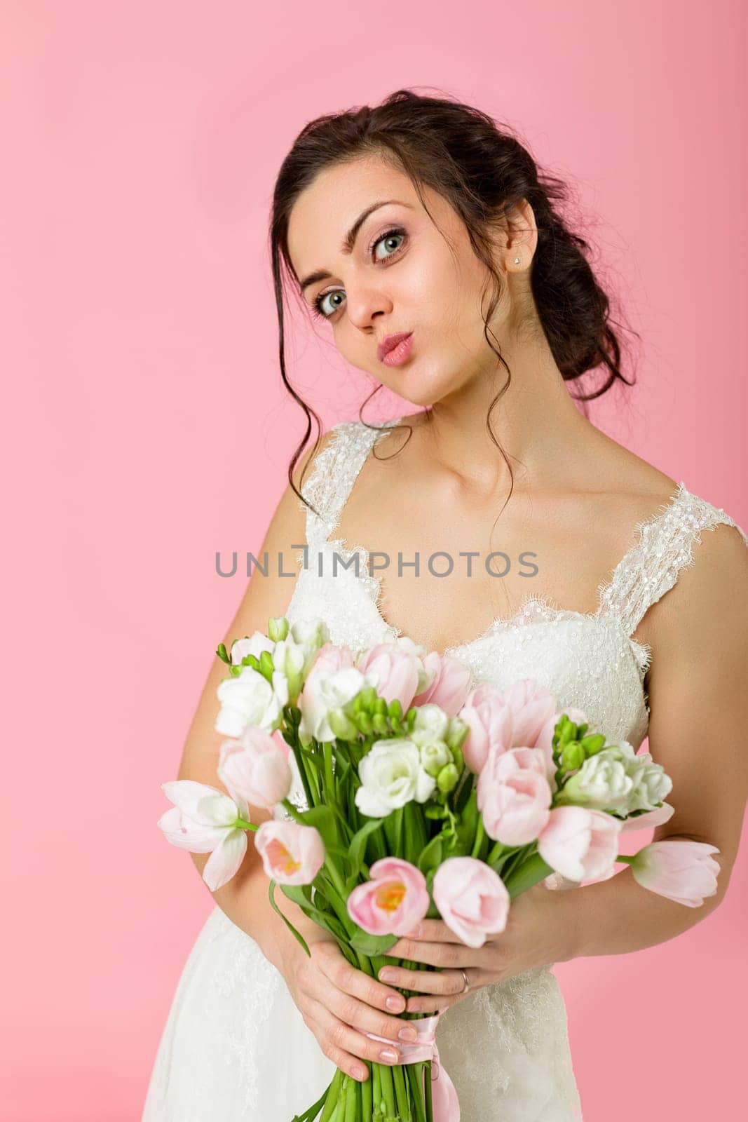 beautiful bride with wedding bouquet of pink tulips on pink background