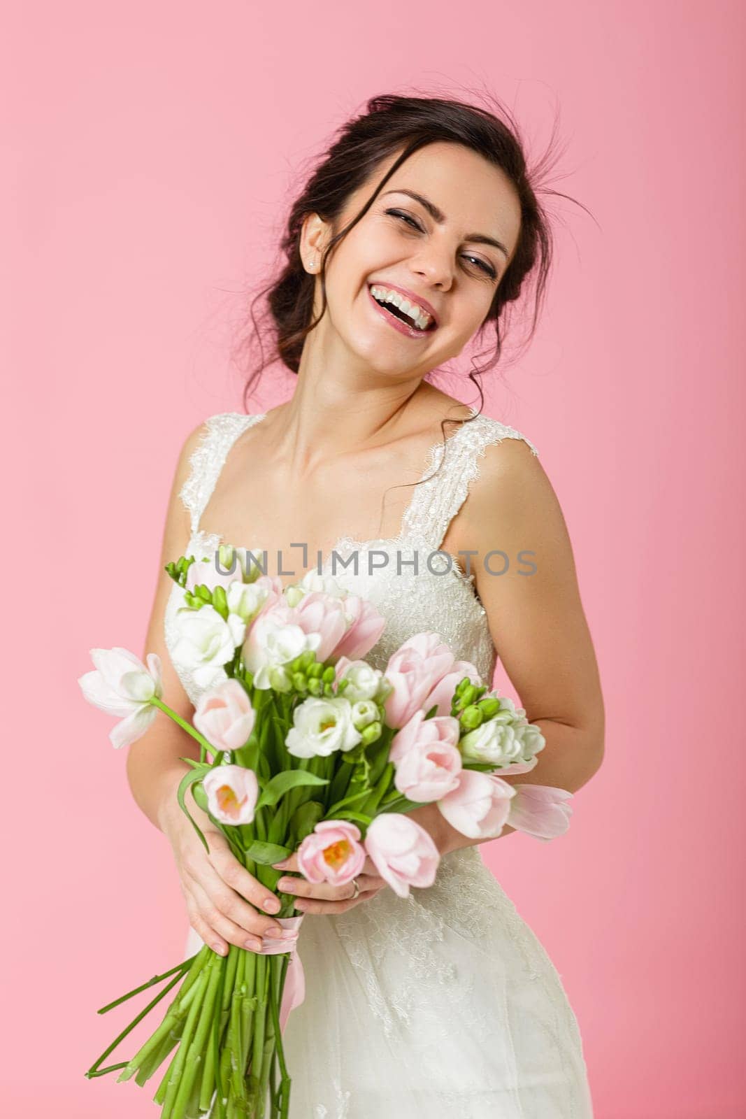 beautiful bride with wedding bouquet of pink tulips on pink background