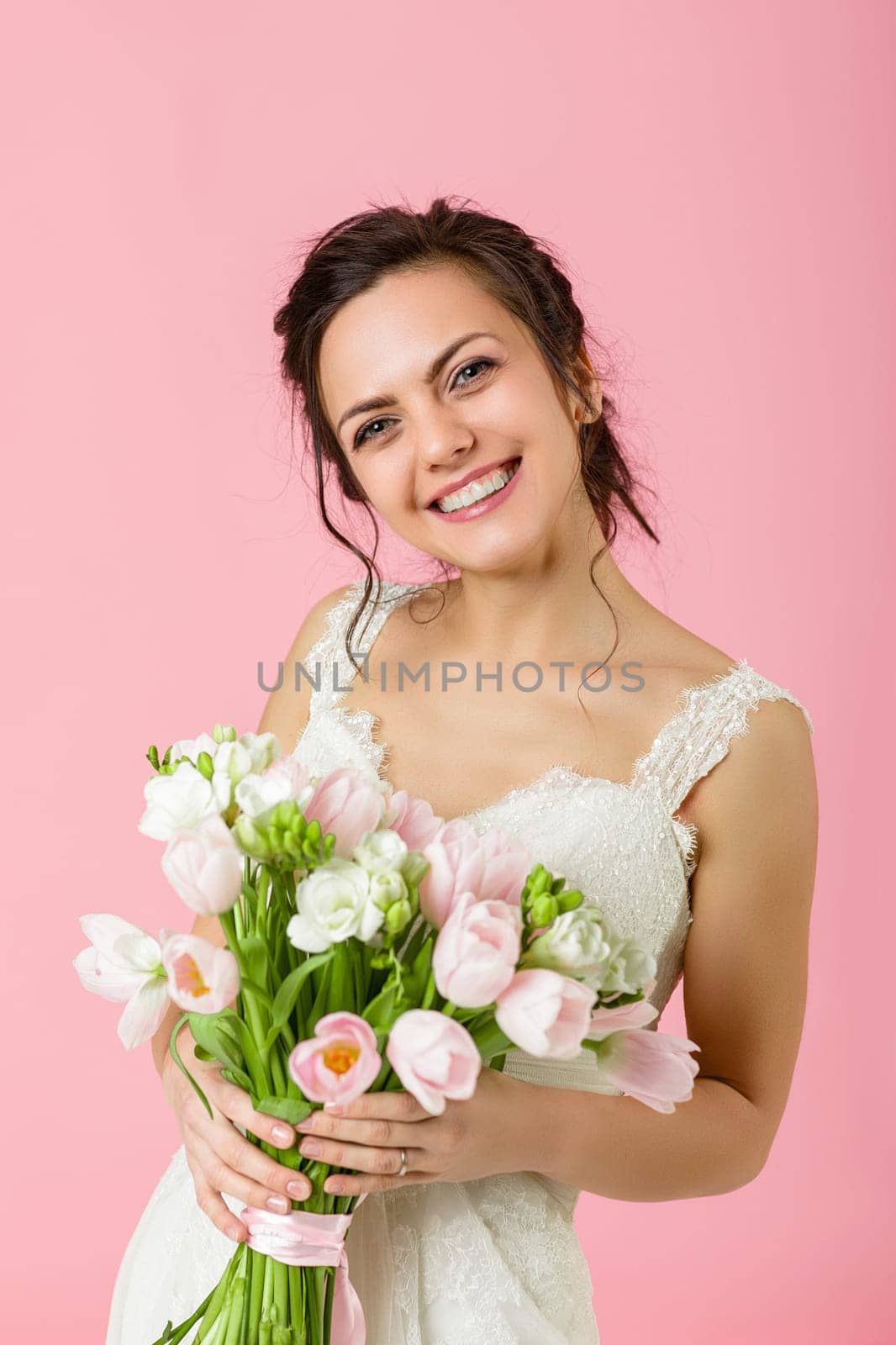 beautiful bride with wedding bouquet of pink tulips on pink background