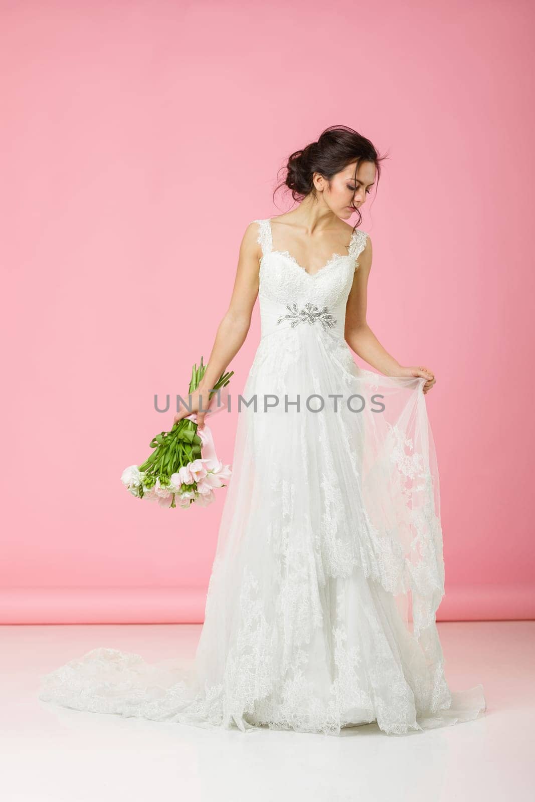 beautiful bride with wedding bouquet of pink tulips on pink background