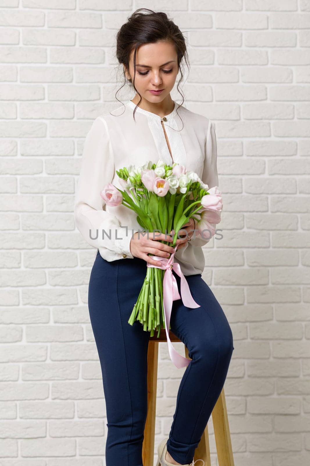 portrait of a beautiful brunette woman with a bouquet of tulips flowers