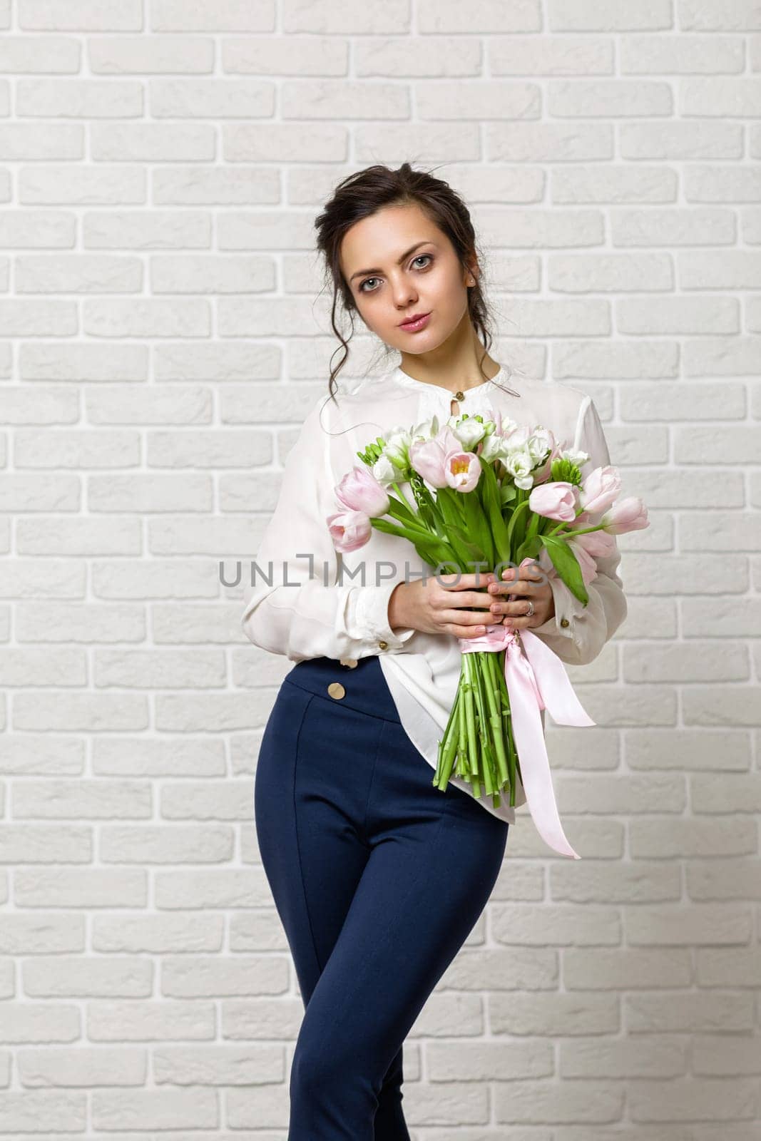 portrait of a beautiful brunette woman with a bouquet of tulips flowers