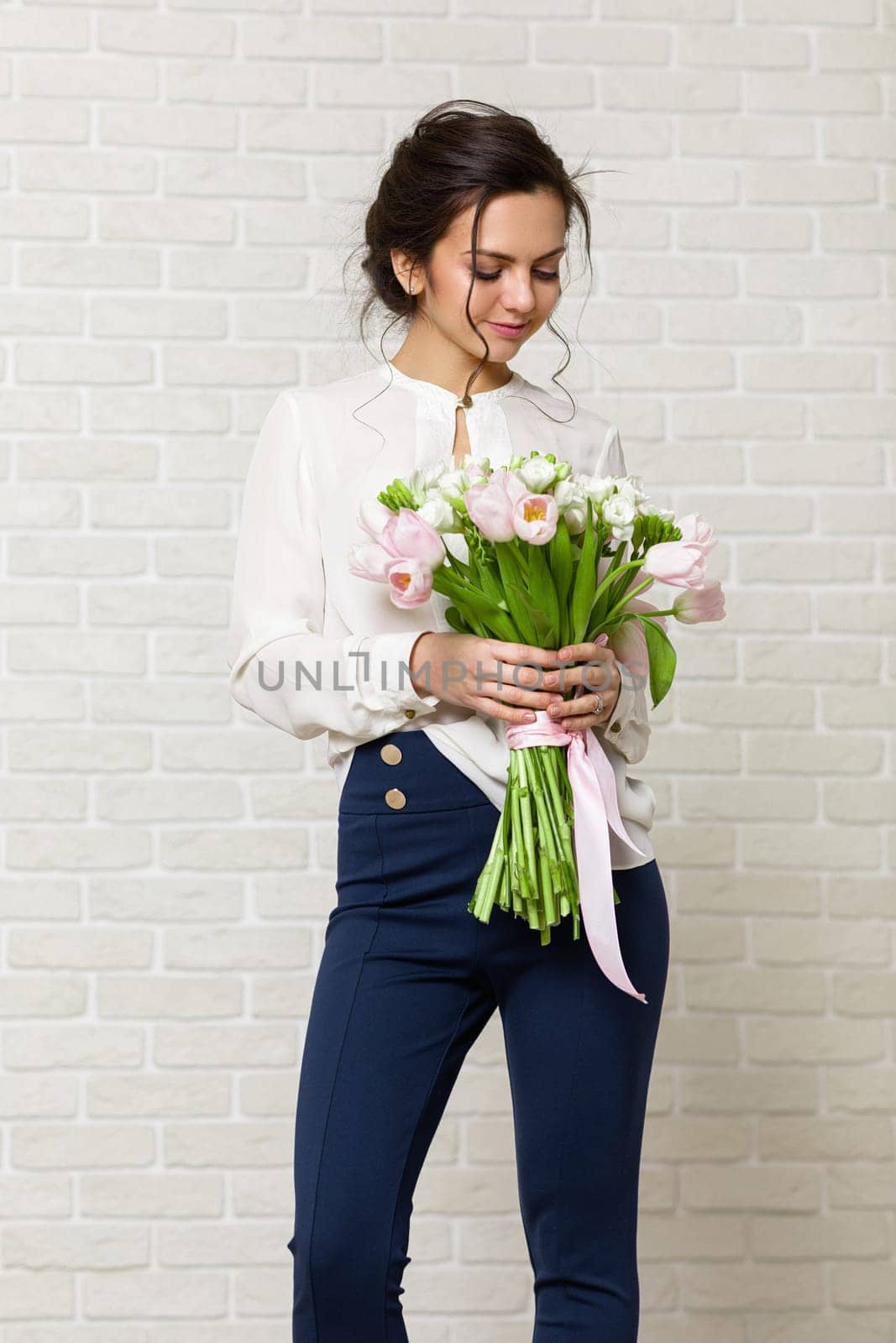 portrait of a beautiful brunette woman with a bouquet of tulips flowers