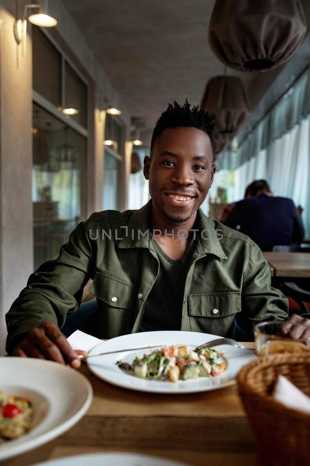young african american man is eating in a restaurant by erstudio