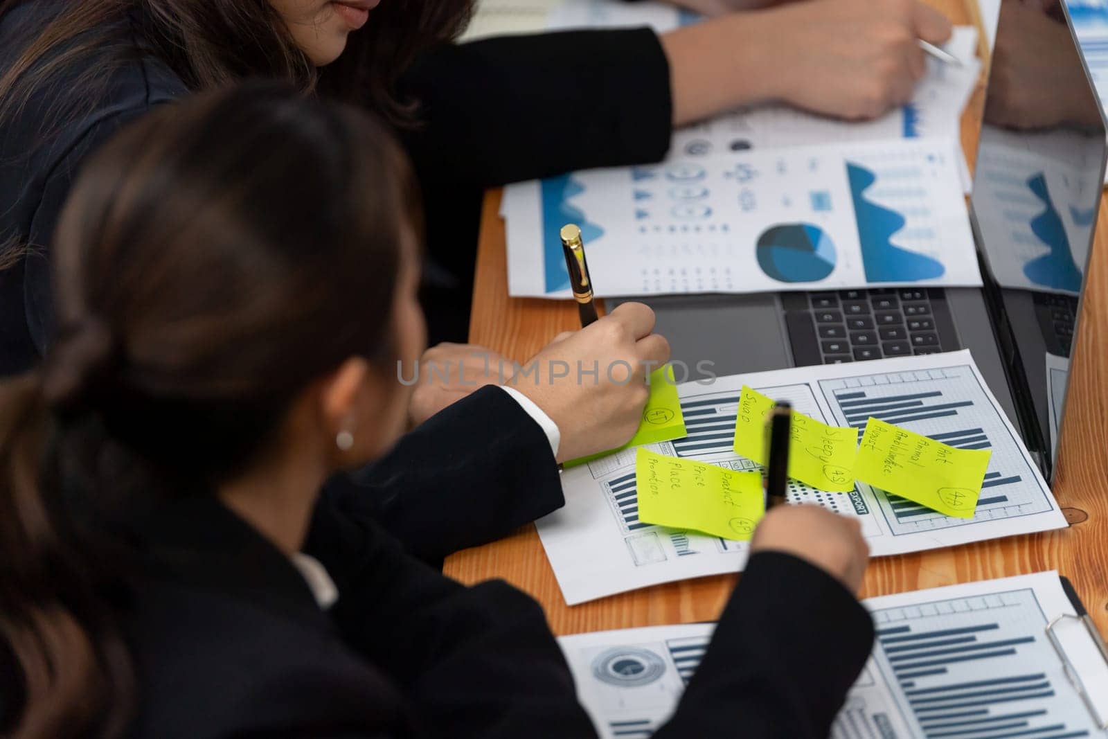 Closeup on BI dashboard on meeting desk with businesspeople analyzing or planning business strategy with hands pointing on financial paper reports as concept of harmony in office workplace.