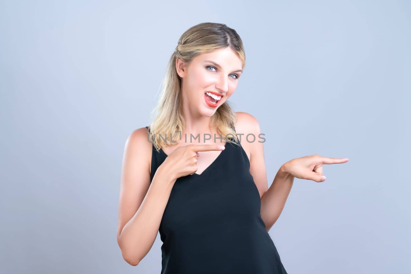 Alluring portrait of beautiful woman with perfect makeup clean skin pointing finger side way in copyspace isolated background. Promotion indicated by hand gesture concept for skincare advertisement.