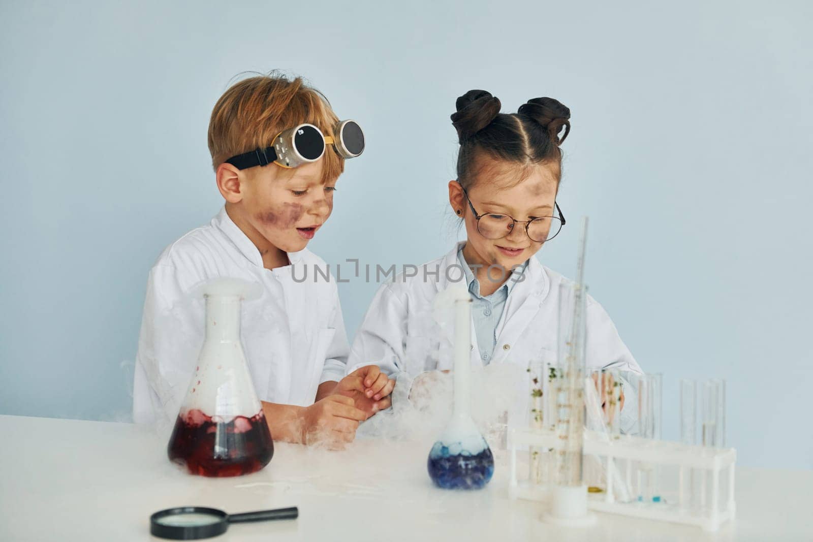 Boy works with liquid in test tubes. Children in white coats plays a scientists in lab by using equipment.