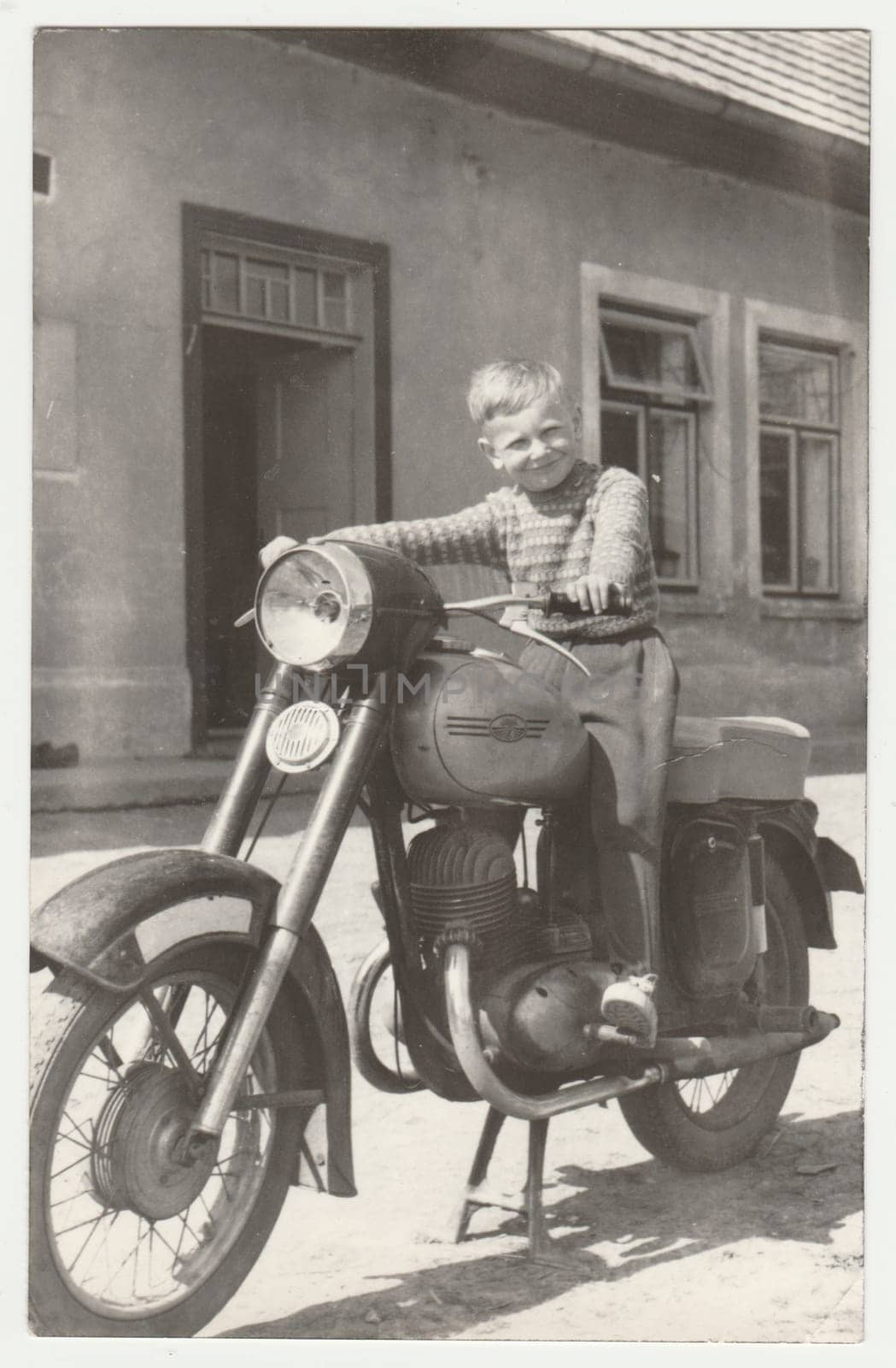 THE CZECHOSLOVAK SOCIALIST REPUBLIC - CIRCA 1960s: Vintage photo shows boy sits on the vintage motorcycle. Retro black and white photography. Circa 1960s.