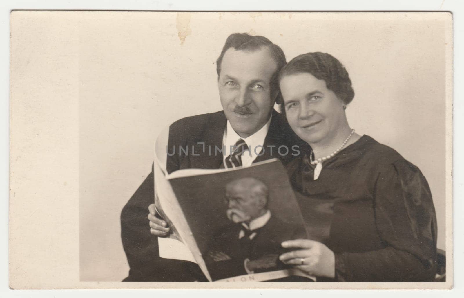 THE CZECHOSLOVAK REPUBLIC - CIRCA 1935: Vintage photo shows a marital couple pose with magazine. The cover page of magazine shows Masaryk - the first Czechoslovak president. Retro black and white photography. Circa 1930s.